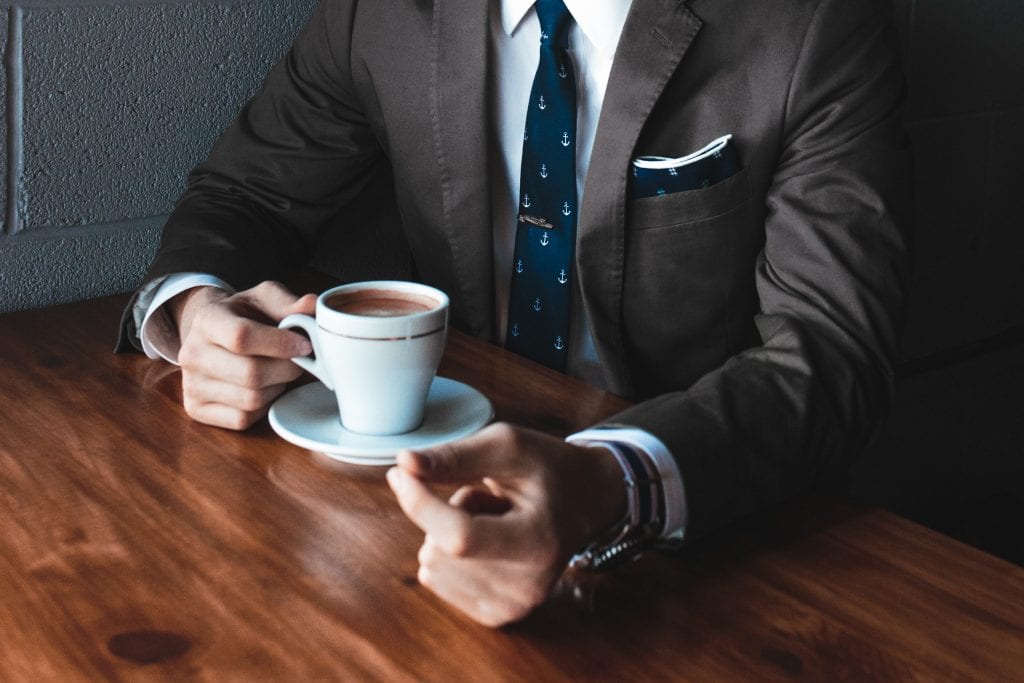 Businessman holding a coffee cup at a table
